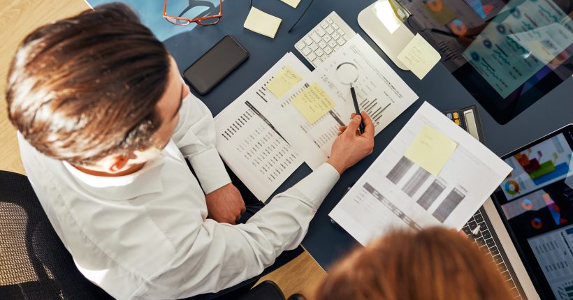 Business colleagues discussing financial data working together in office. People entrepreneurs working with charts and tables on computer. Two people working together. Workmates talking about project