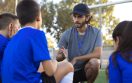 side-view-football-trainer-helping-kids