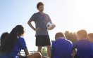 man-training-kids-playing-football-front-view